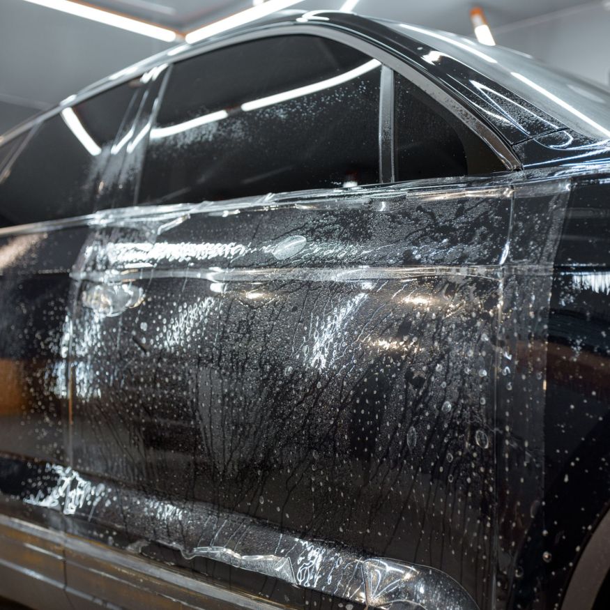 Wet car body during a protective film applying at the vehicle service garage